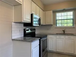 a kitchen with granite countertop white cabinets sink and stainless steel appliances