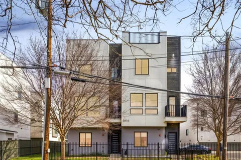 a view of a white house next to a large tree