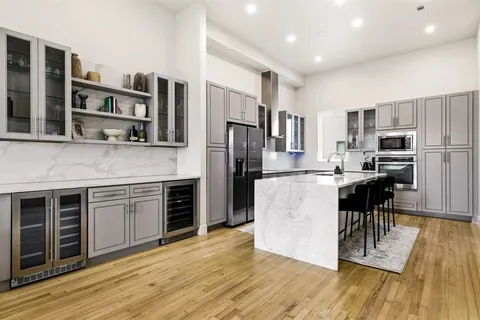 a kitchen with stainless steel appliances granite countertop a refrigerator a stove top oven and a wooden floors