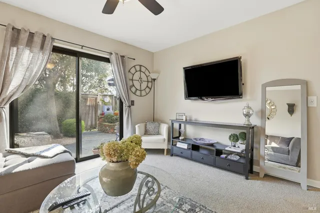 a living room with furniture a flat screen tv and a floor to ceiling window