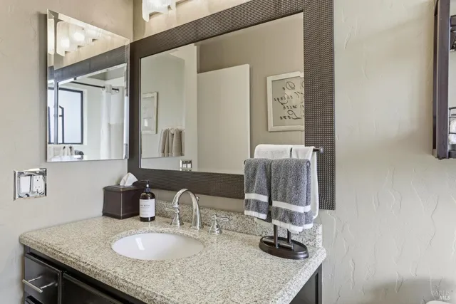 a bathroom with a granite countertop sink and a mirror