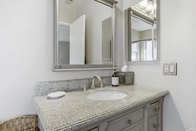 a bathroom with a granite countertop sink and a mirror