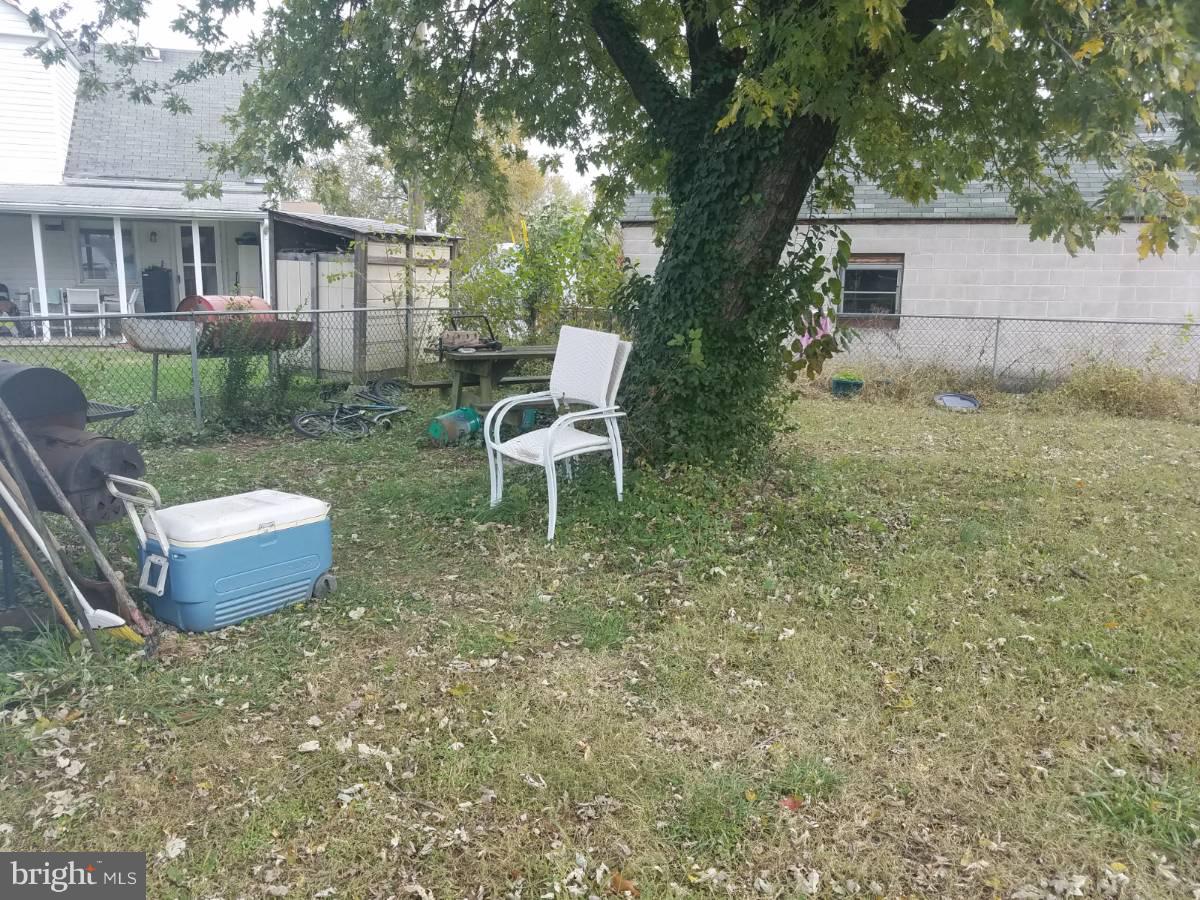 7404 Belclare Road Baltimore, MD 21222 - Photo 4 of 5 a view of a backyard with table and chairs potted plants and large tree