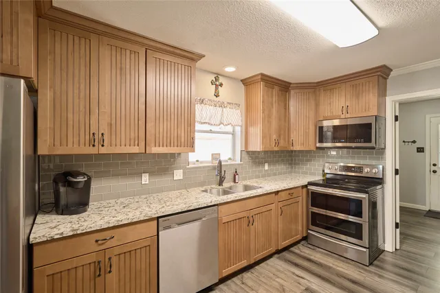 a large kitchen with stainless steel appliances granite countertop a stove refrigerator and cabinets