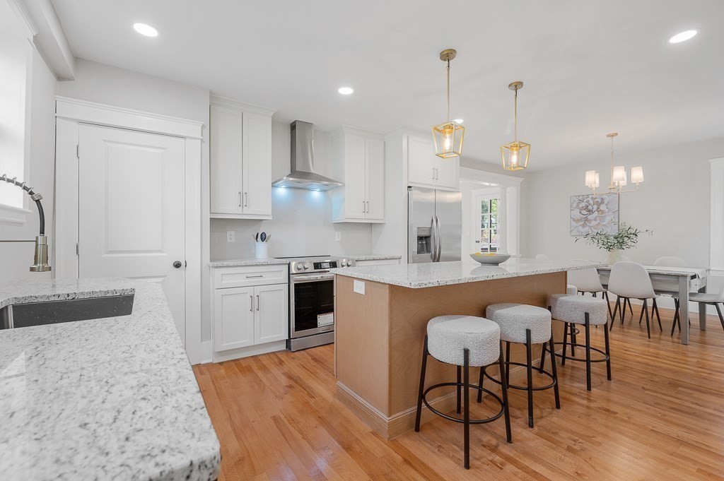 47 Brighton Road Worcester, MA 01606 - Photo 13 of 39 a large kitchen with granite countertop a stove a sink a dining table and chairs with wooden floor