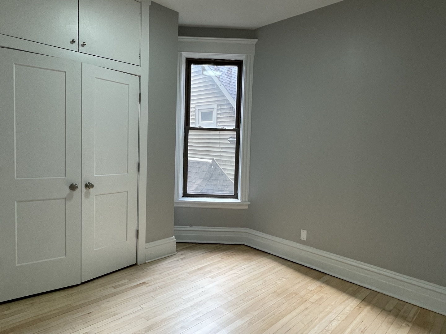 4032 North Wolcott Avenue, Unit 2R Chicago, IL 60613 - Photo 2 of 10 a view of an empty room with wooden floor and a window