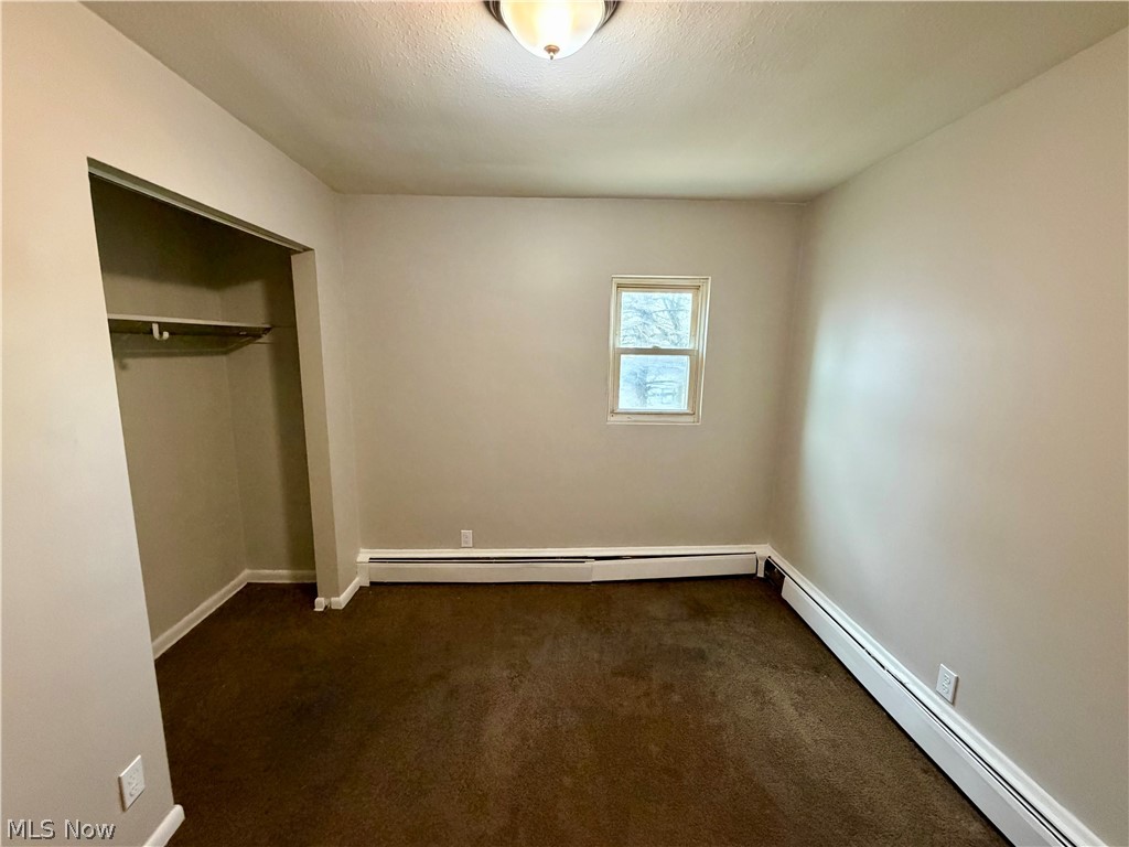 4652 Warner Road, Unit 3 Cleveland, OH 44125 - Photo 12 of 13 Unfurnished bedroom featuring a baseboard radiator, dark carpet, and a closet