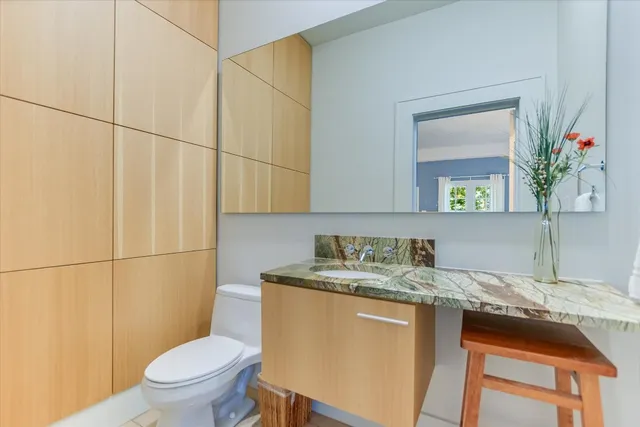 a bathroom with a granite countertop sink toilet and mirror