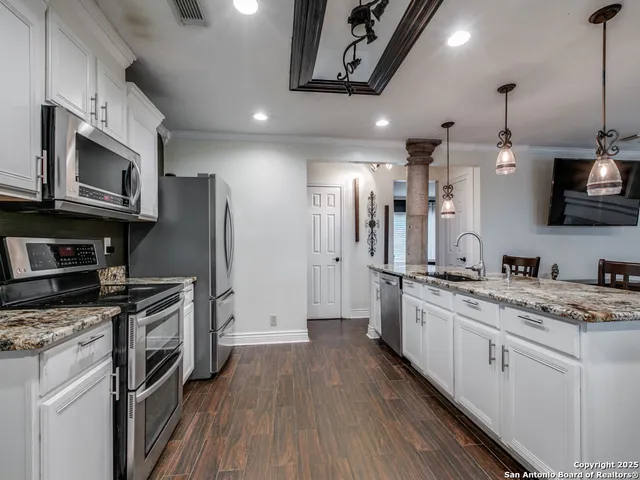 a kitchen with stainless steel appliances granite countertop a refrigerator a stove a sink and a microwave