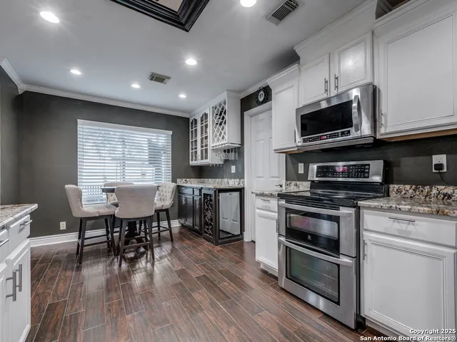 a kitchen with stainless steel appliances kitchen island granite countertop a stove top oven a sink dishwasher a dining table and chairs with wooden floor