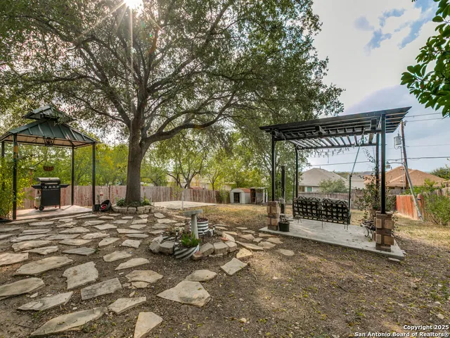a view of a backyard with large trees and wooden fence