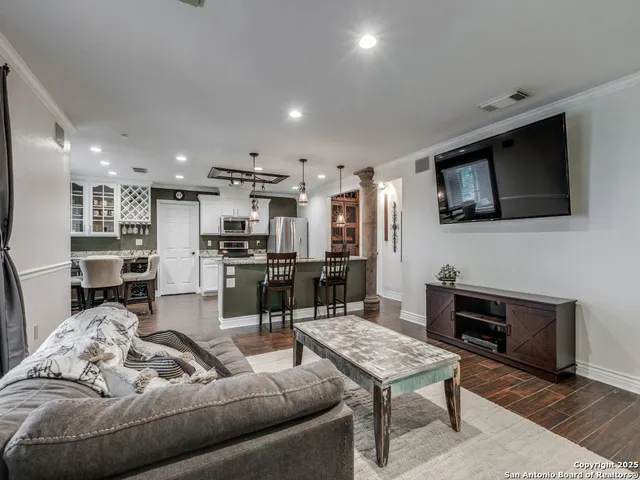 a living room with furniture kitchen view and a wooden floor