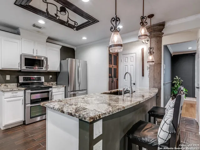 a kitchen with kitchen island granite countertop a sink appliances and cabinets
