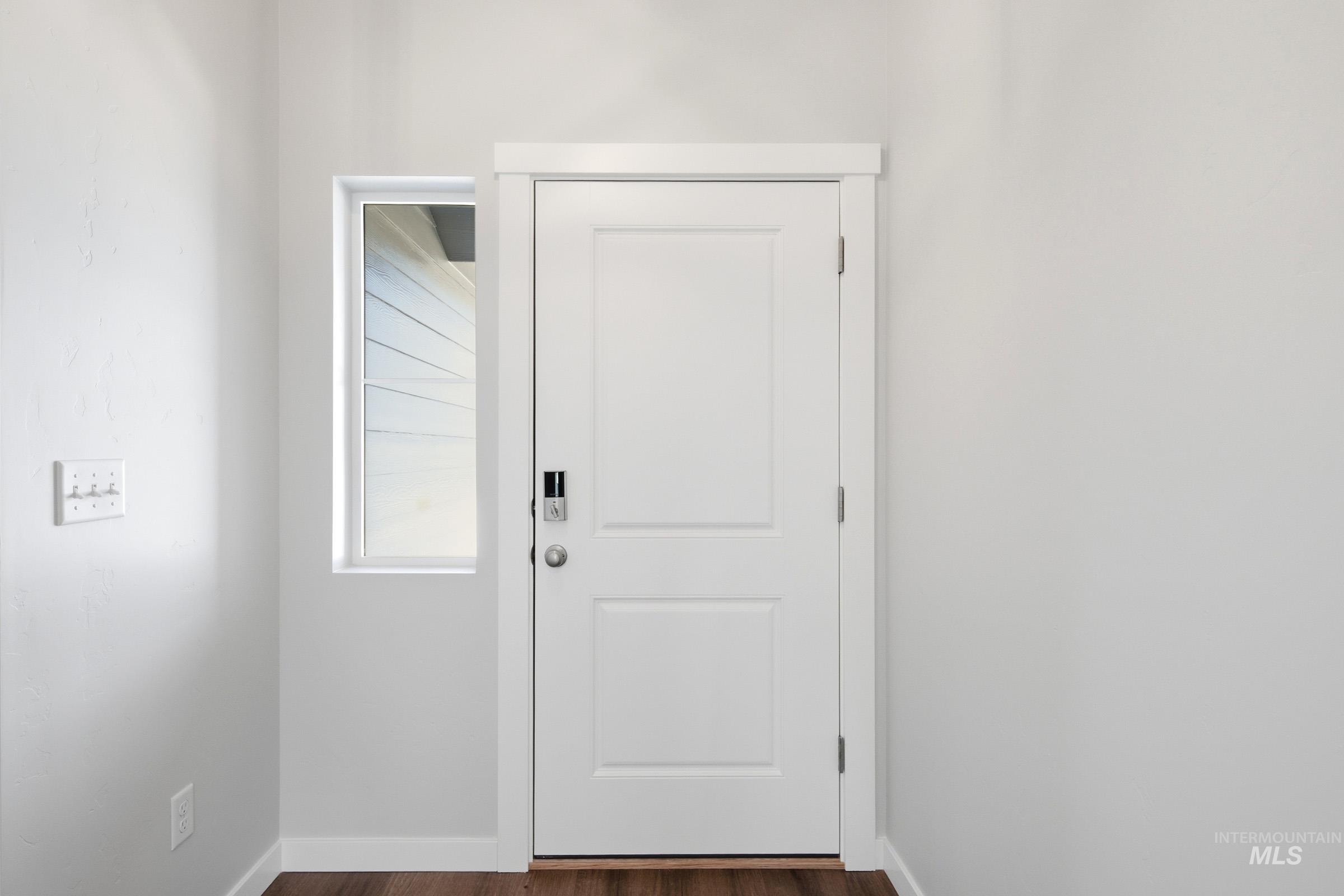 12877 Decatur Street Nampa, ID 83651 - Photo 2 of 22 Entryway featuring a white paneled door with a smart lock, an adjacent vertical window, wood-finish flooring, and crisp white trim