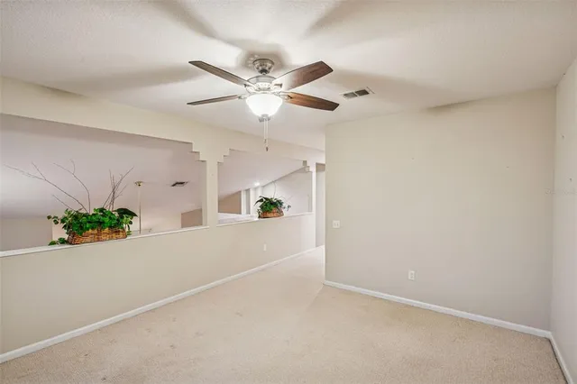 an empty room with potted plant and ceiling fan