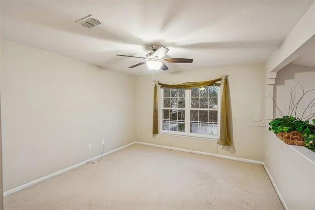an empty room with potted plant and a ceiling fan