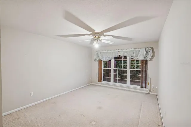 an empty room with windows and ceiling fan