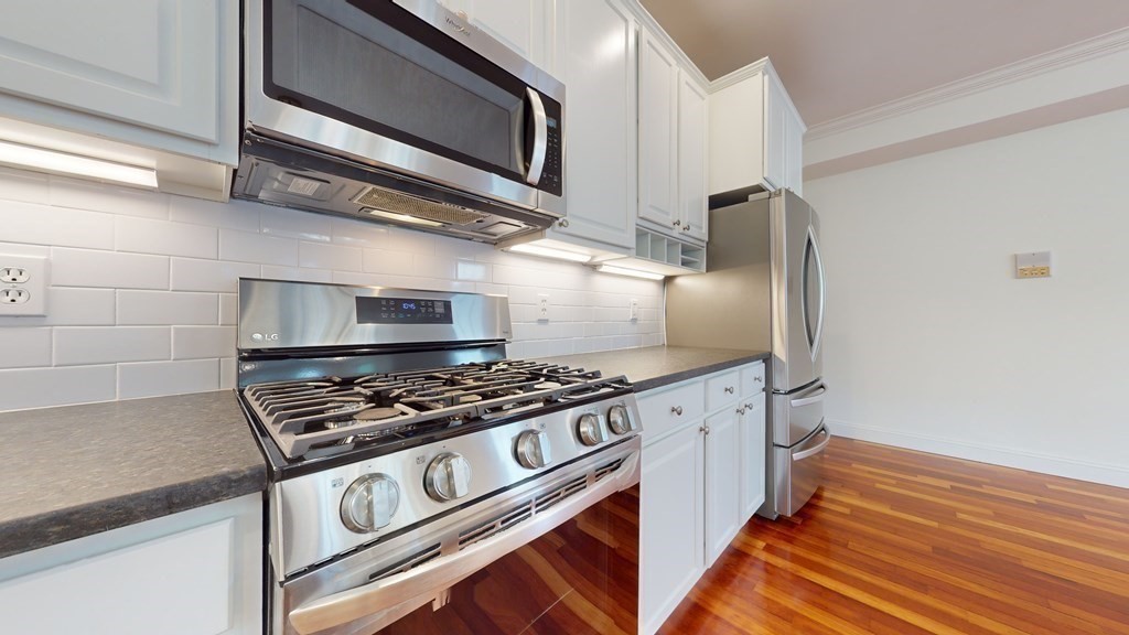 604 Freeport Street, Unit PH 5 Boston, MA 02122 - Photo 12 of 38 a kitchen with stainless steel appliances granite countertop a stove and a microwave