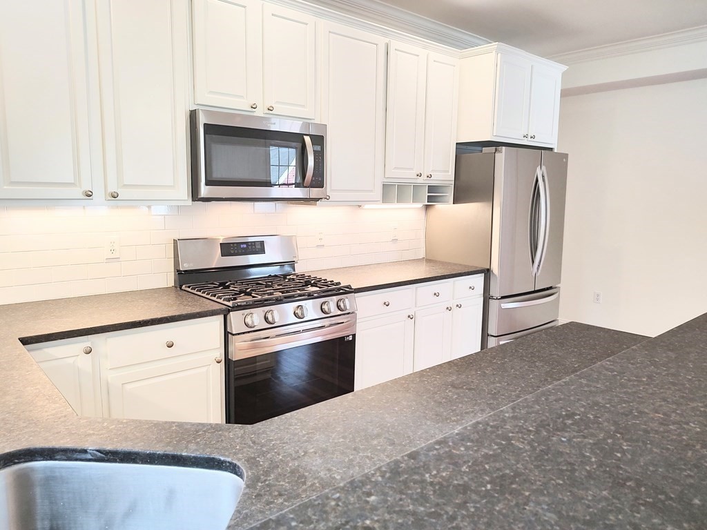 604 Freeport Street, Unit PH 5 Boston, MA 02122 - Photo 13 of 38 a kitchen with granite countertop white cabinets and stainless steel appliances