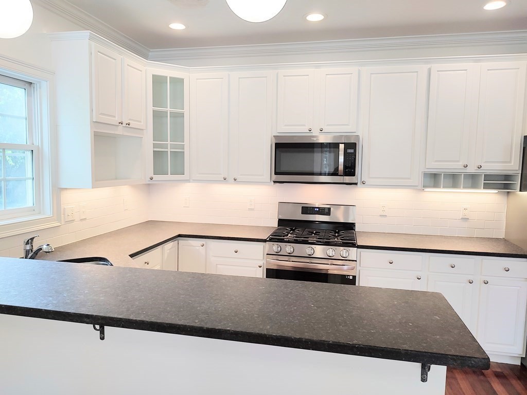 604 Freeport Street, Unit PH 5 Boston, MA 02122 - Photo 14 of 38 a kitchen with stainless steel appliances a stove microwave and cabinets