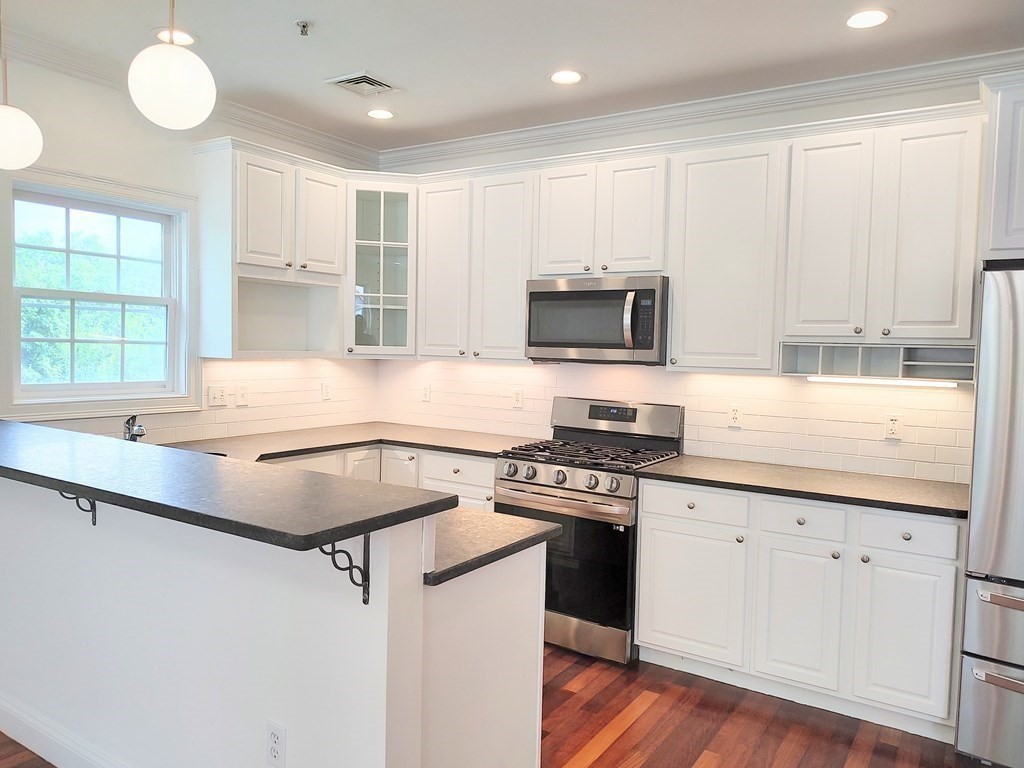 604 Freeport Street, Unit PH 5 Boston, MA 02122 - Photo 15 of 38 a kitchen with granite countertop a sink appliances cabinets and a counter top space