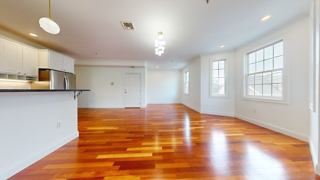 604 Freeport Street, Unit PH 5 Boston, MA 02122 - Photo 6 of 38 a view of kitchen and empty room with wooden floor
