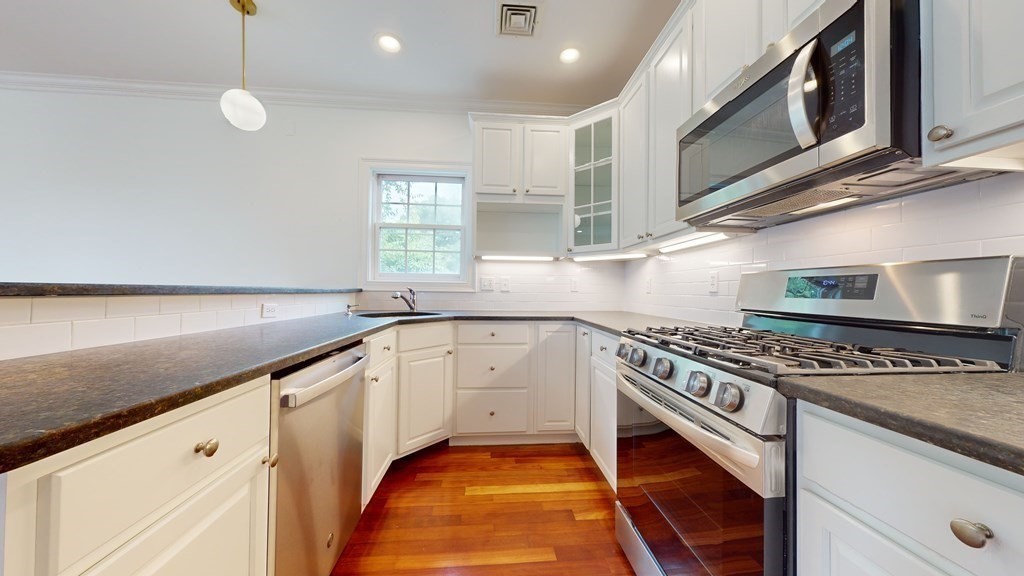 604 Freeport Street, Unit PH 5 Boston, MA 02122 - Photo 10 of 38 a kitchen with stainless steel appliances granite countertop a stove a sink and a microwave