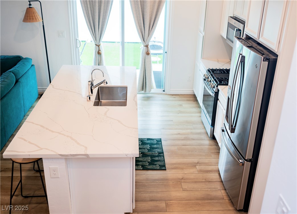 7342 North Decatur Boulevard, Unit 5 North Las Vegas, NV 89084 - Photo 7 of 29 Kitchen featuring appliances with stainless steel finishes, a sink, white cabinetry, and light wood finished floors