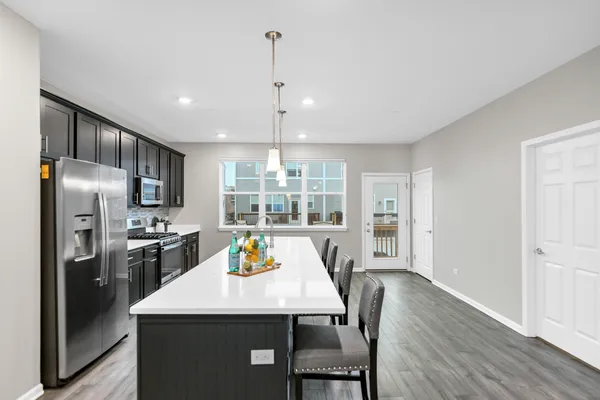 a kitchen with stainless steel appliances a dining table chairs refrigerator and stove