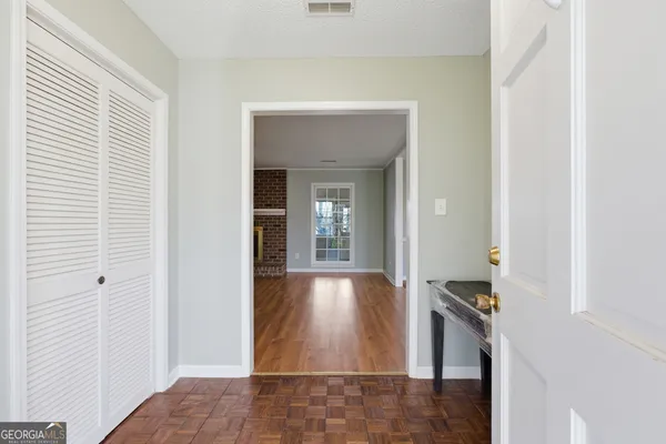 a view of an empty room with wooden floor fireplace and a window