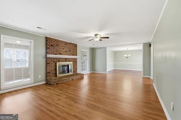 an empty room with windows a fireplace and wooden floor