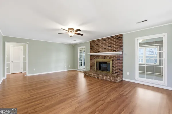 a view of a livingroom with a ceiling fan fireplace and wooden floor