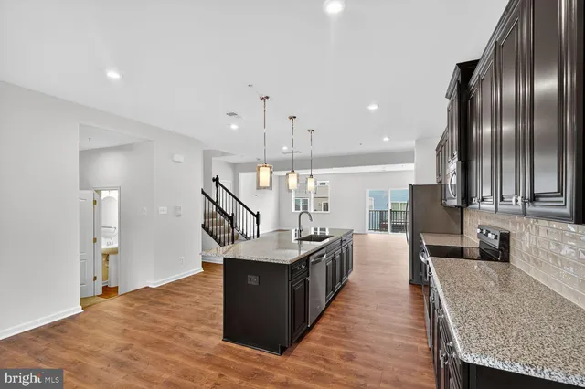 a kitchen with stainless steel appliances kitchen island granite countertop a table chairs and a refrigerator