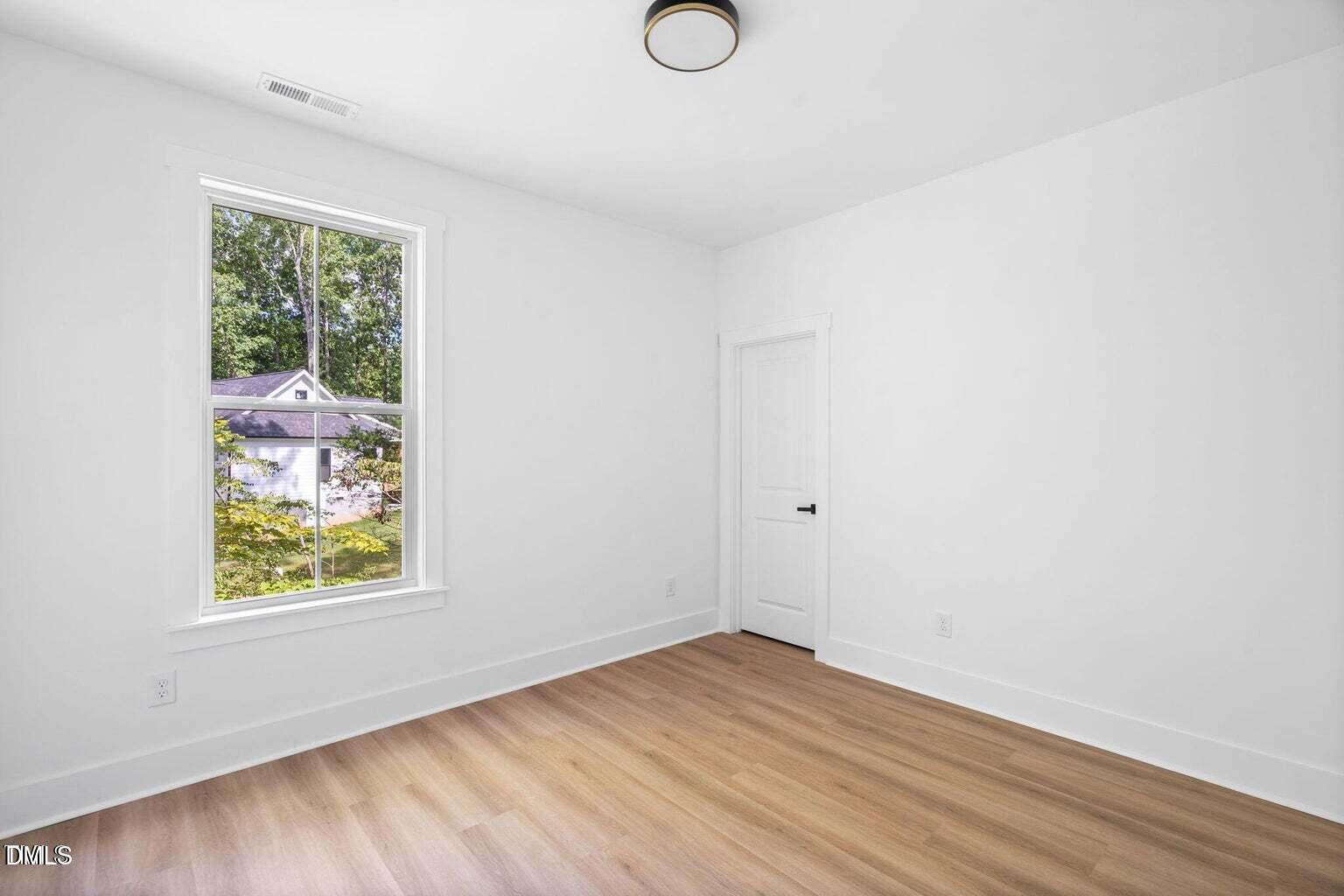712 Oaks Lane Road Timberlake, NC 27583 - Photo 32 of 49 an empty room with wooden floor and window