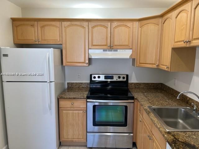 594 Saxony M, Unit 594 Delray Beach, FL 33446 - Photo 4 of 9 a kitchen with granite countertop a sink stove and refrigerator
