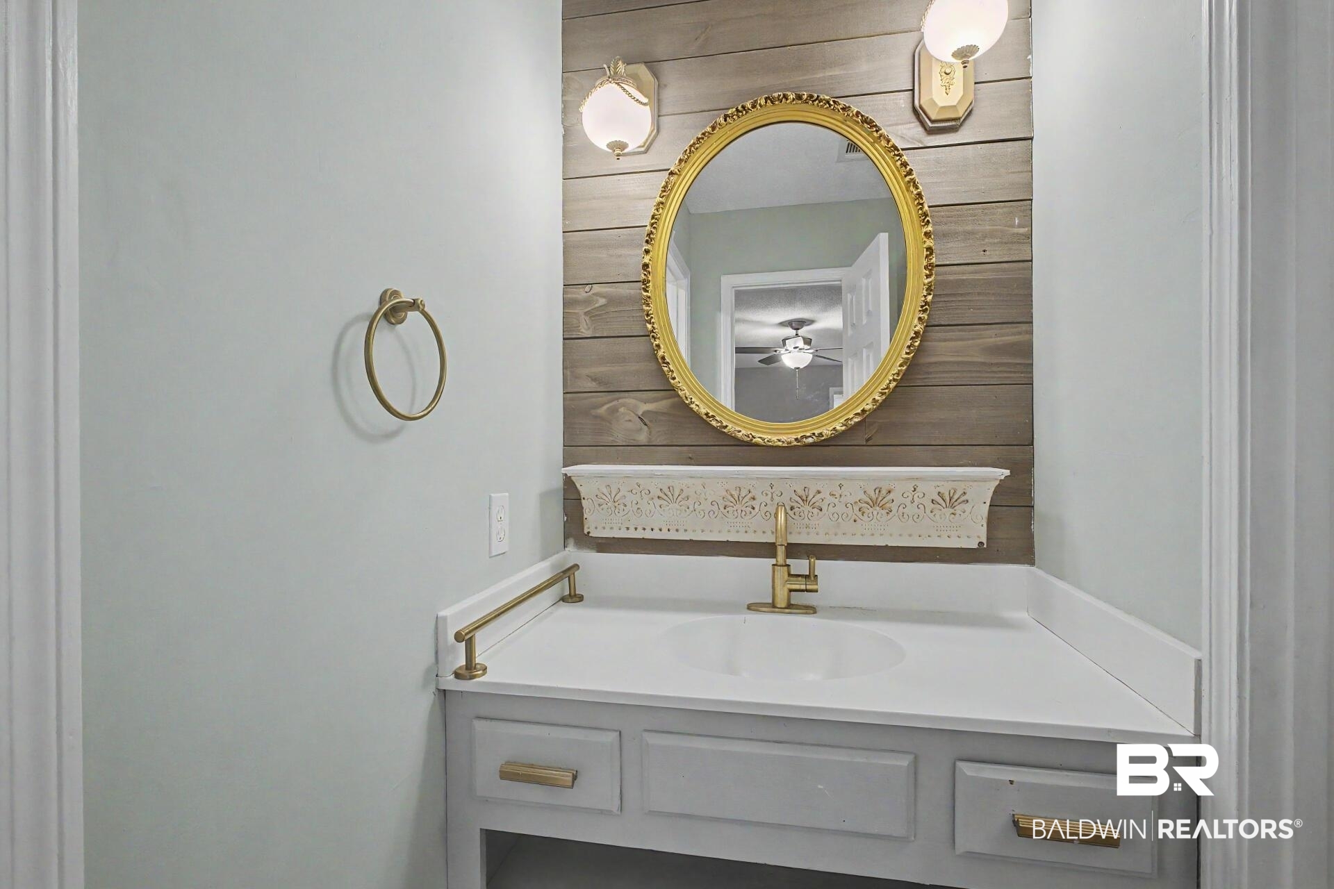 3791 Robinsonville Road Atmore, AL 36502 - Photo 45 of 47 Vanity featuring a white countertop with an undermount sink, brass-finish faucet, and shiplap-style accent wall
