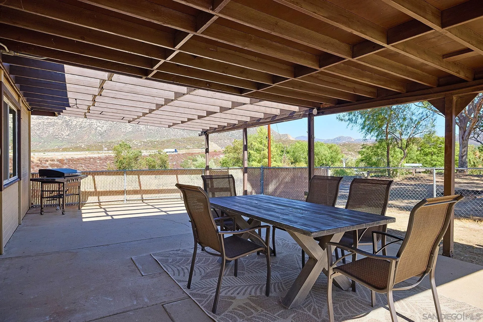 6185 Alpine Boulevard Alpine, CA 91901 - Photo 24 of 39 a view of a patio with table and chairs under an umbrella with a barbeque