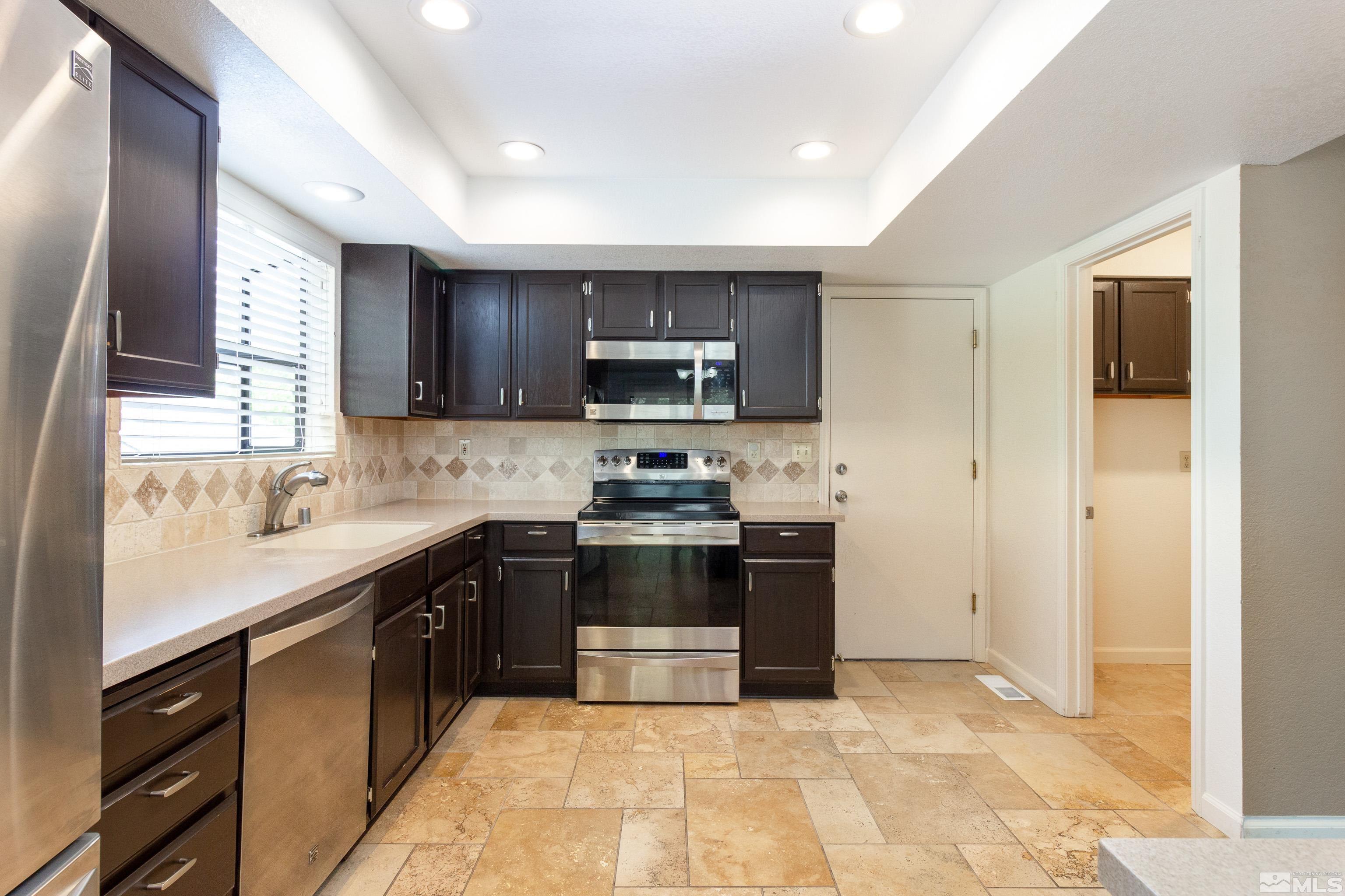 5331 Coit Drive Reno, NV 89523 - Photo 26 of 28 a kitchen with stainless steel appliances granite countertop a stove top oven a sink dishwasher and a refrigerator with wooden floor