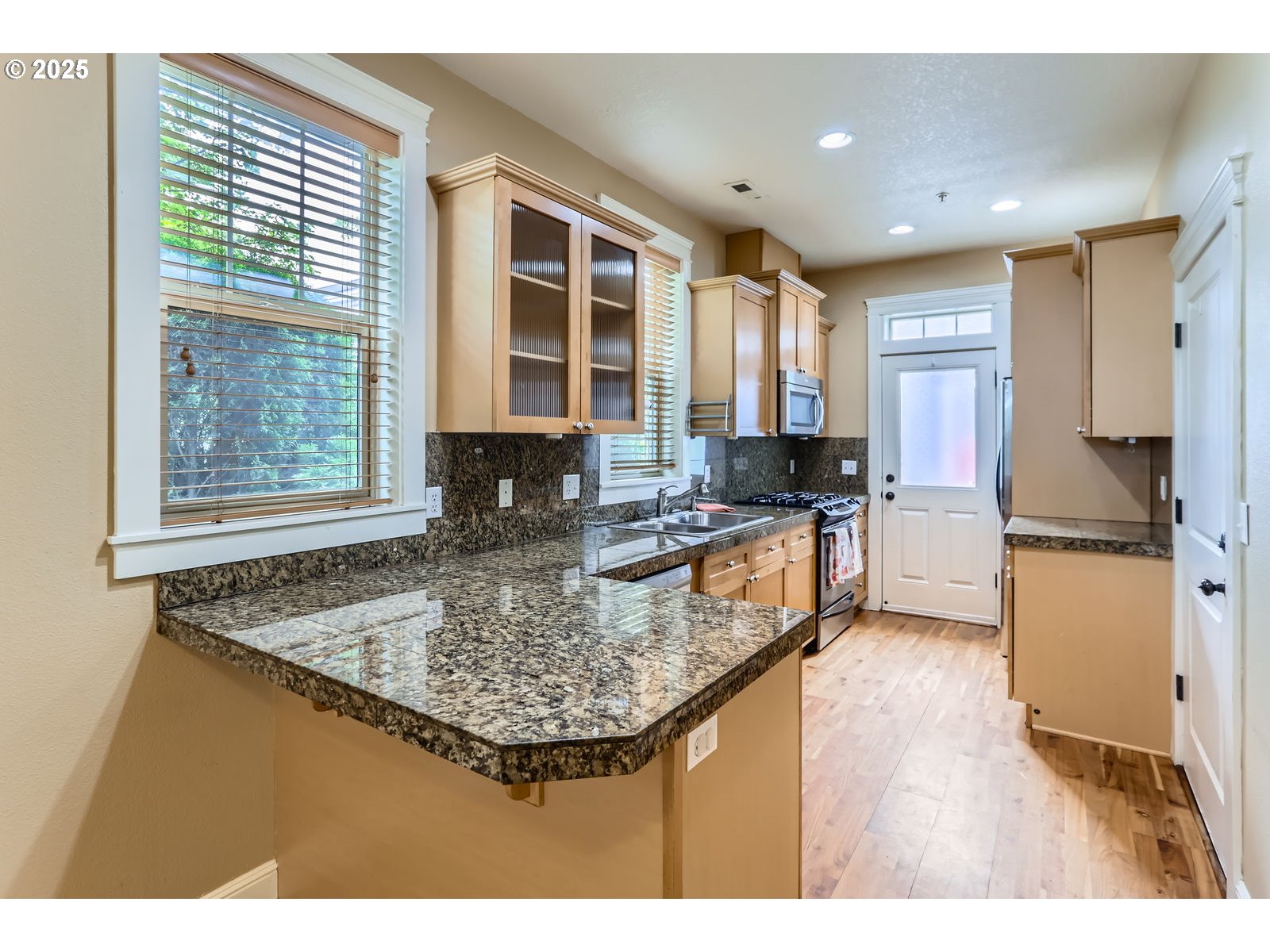 343 Northeast Bryant Street Portland, OR 97211 - Photo 9 of 26 a kitchen with kitchen island granite countertop a stove a sink a refrigerator and blue cabinets with wooden floor