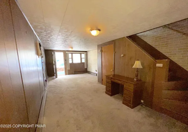 a view of a hallway with stainless steel appliances wooden floor and living room view