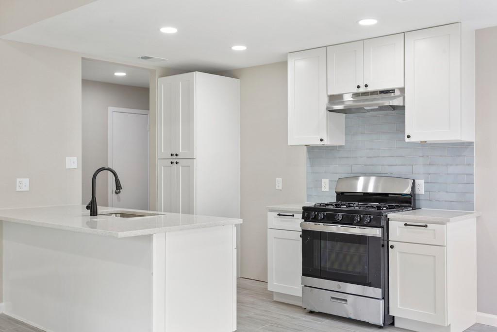 9604 Crown Ridge Road Austin, TX 78753 - Photo 3 of 24 Modern kitchen with white shaker cabinets and a practical island with an integrated sink.