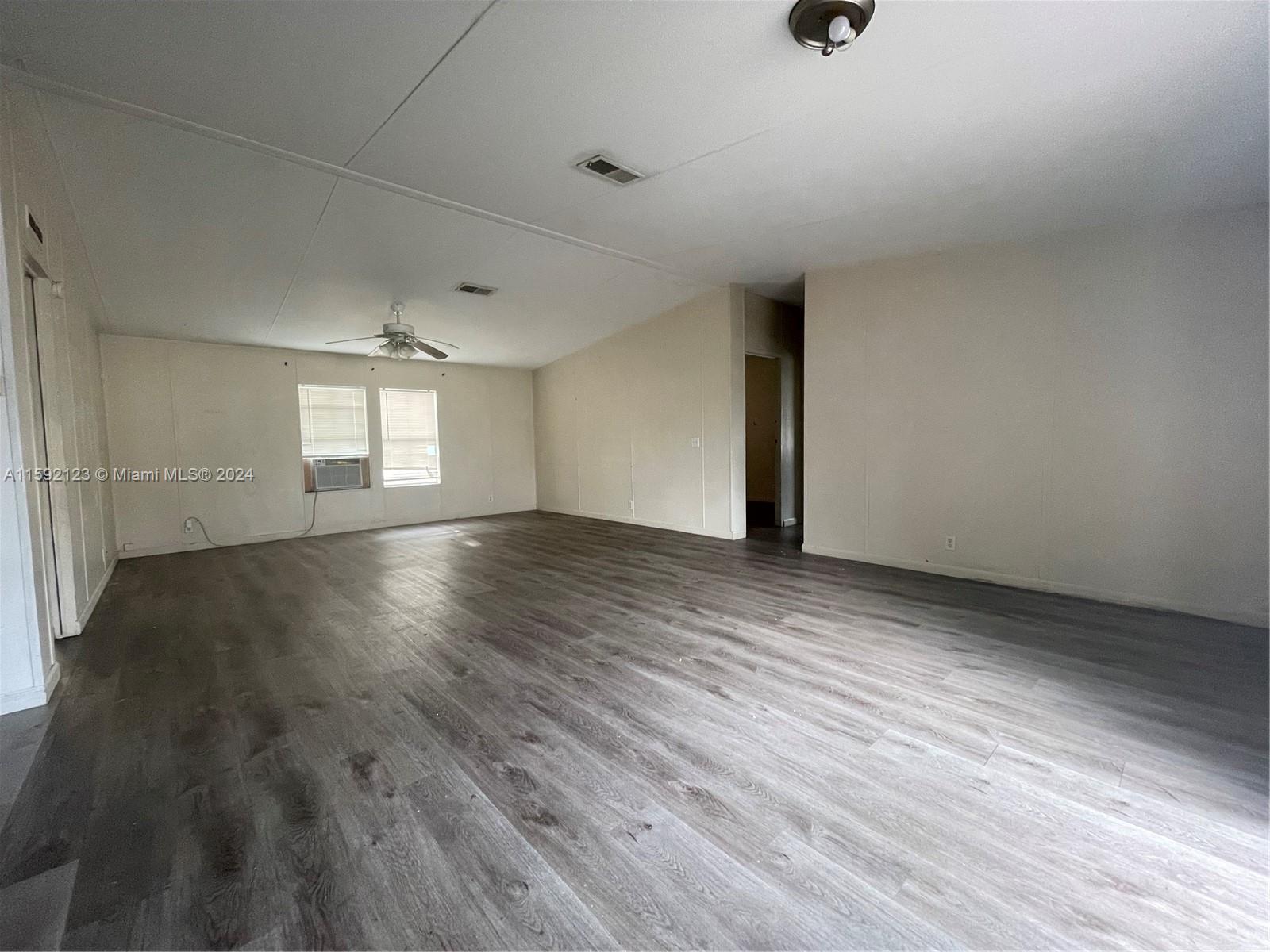 10128 Marlin Drive, Unit 1 Boca Raton, FL 33428 - Photo 7 of 17 an empty room with wooden floor and windows