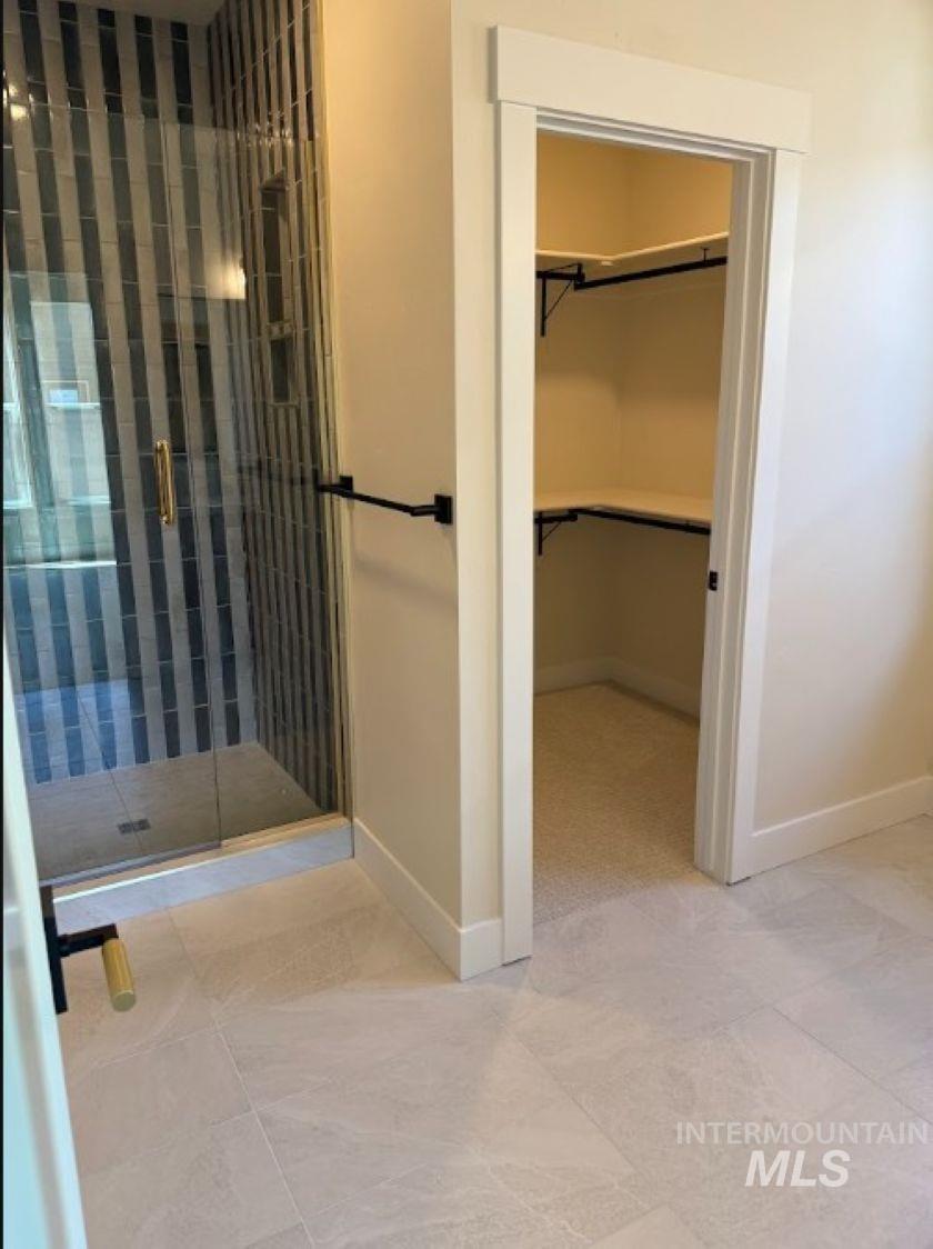 683 West Wrangler Street Meridian, ID 83646 - Photo 14 of 23 Shower with glass enclosure, vertical striped tile, and gold-tone hardware