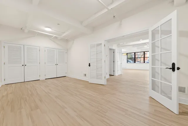 an empty room with wooden floor and windows