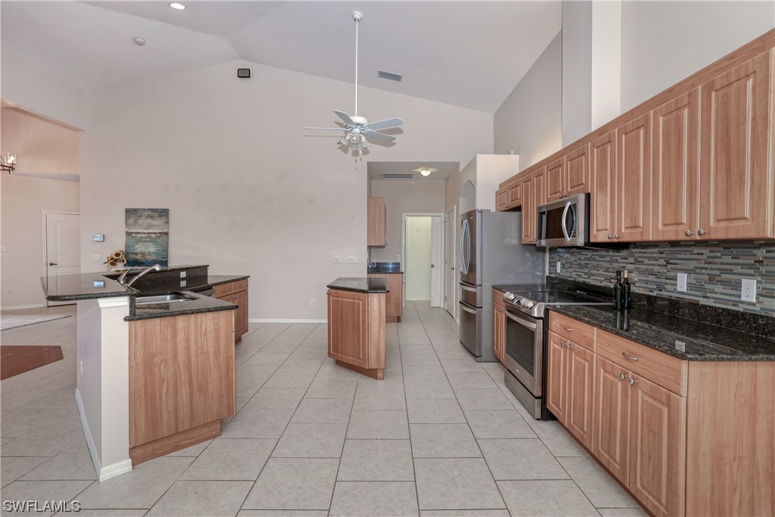 17501 Homewood Road Fort Myers, FL 33967 - Photo 19 of 50 a kitchen with stainless steel appliances granite countertop a stove top oven a sink dishwasher and a refrigerator with wooden cabinets