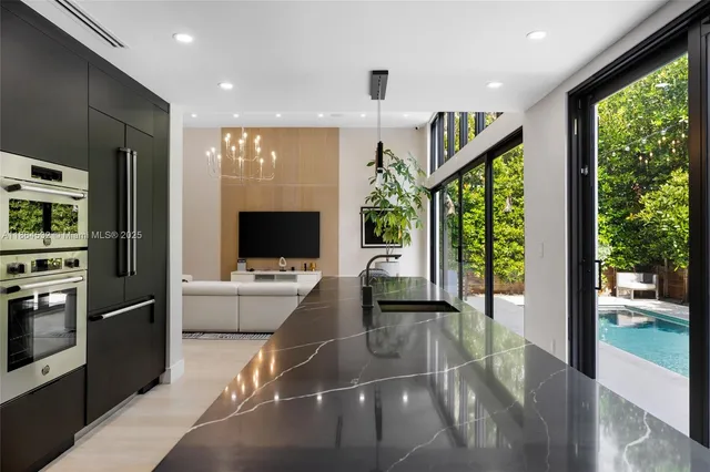 a living room with furniture a chandelier and a floor to ceiling window