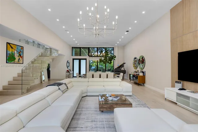 a view of a dining room with furniture a chandelier and large windows