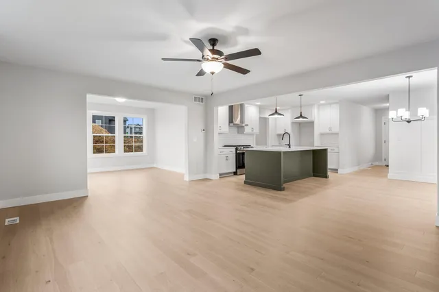 a view of a kitchen with a stove cabinets a ceiling fan and wooden floor