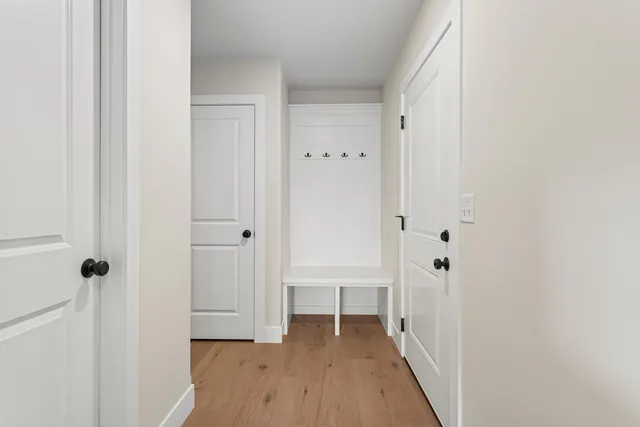 a view of a hallway with wooden floor and a bathroom