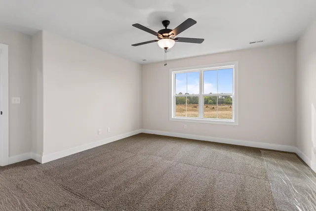 an empty room with ceiling fan and windows